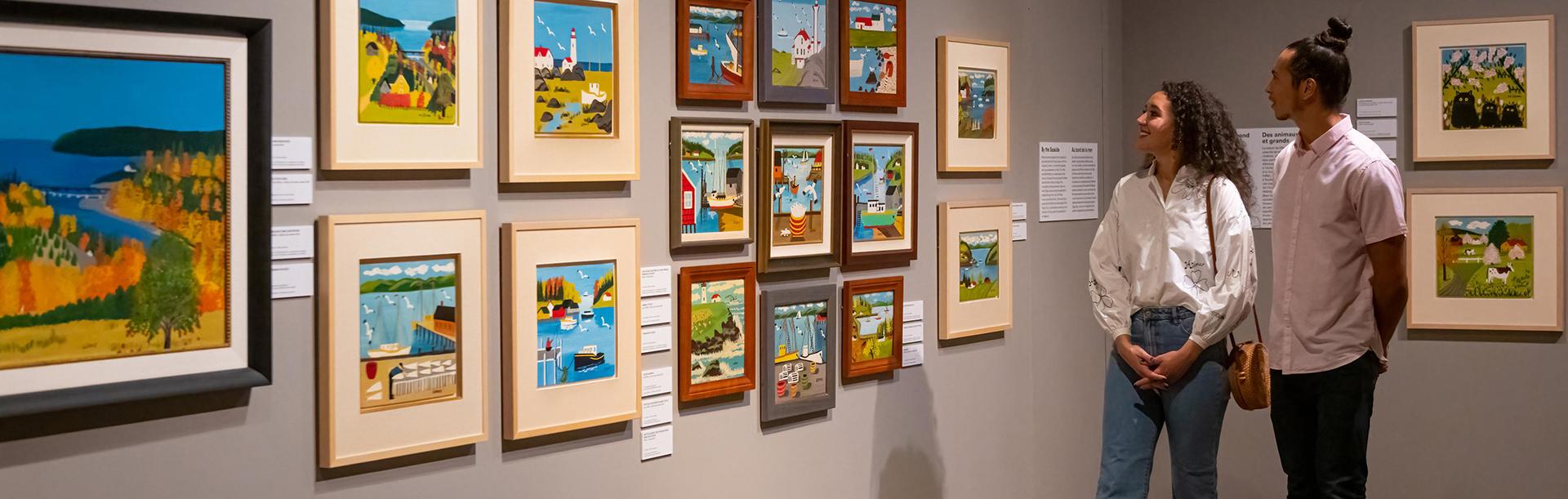 A couple examines artwork by Maud Lewis at the Art Gallery of Greater Victoria in Victoria, BC