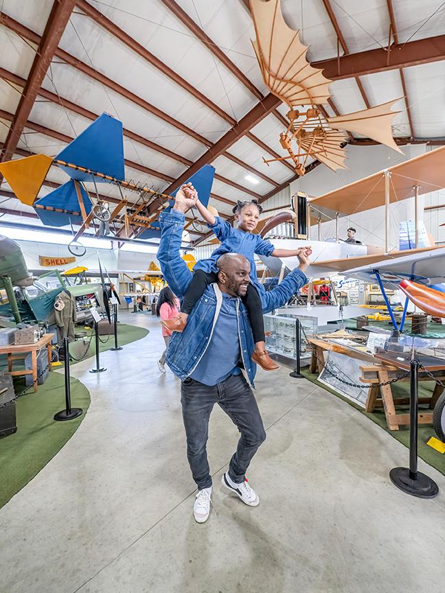 A father gives his daughter a piggyback ride through the BC Aviation Museum in Victoria, BC