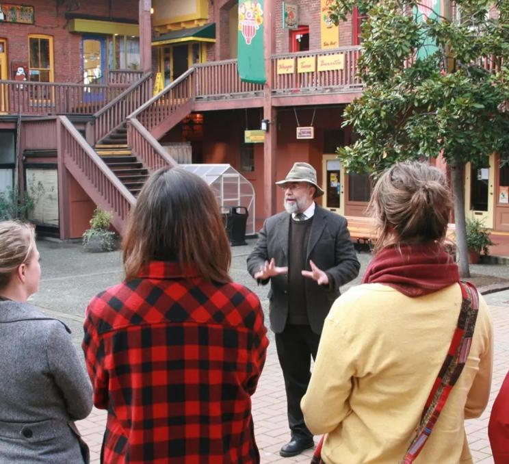 A guide leads a tour group through Market Square during a Discovery Walks History Tour in Victoria, BC