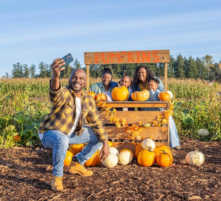 A young family poses for a photo in the pumpkin patch at Ocean View Estates in Victoria, BC