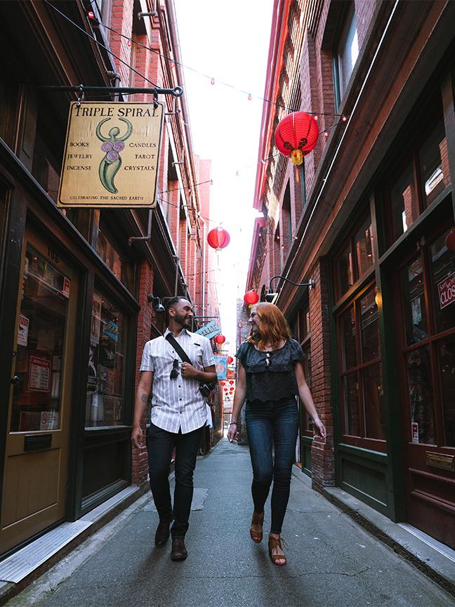 A couple walks through Fan Tan Alley, Canada's narrowest street, in Victoria, BC's historic Chinatown