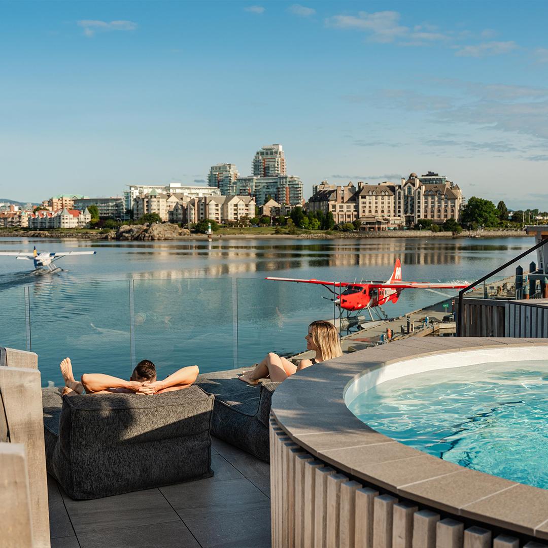A couple relaxes at HAVN Saunas while they watch a seaplane take off on the Inner Harbour in Victoria, BC
