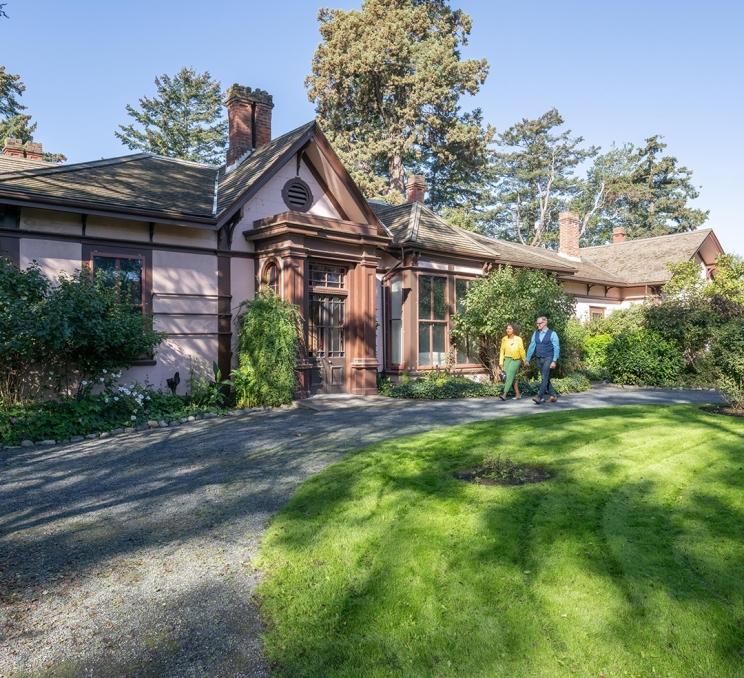 A couple walks hand-in-hand along a pathway outside of Point Ellice House Museum & Gardens in Victoria, BC