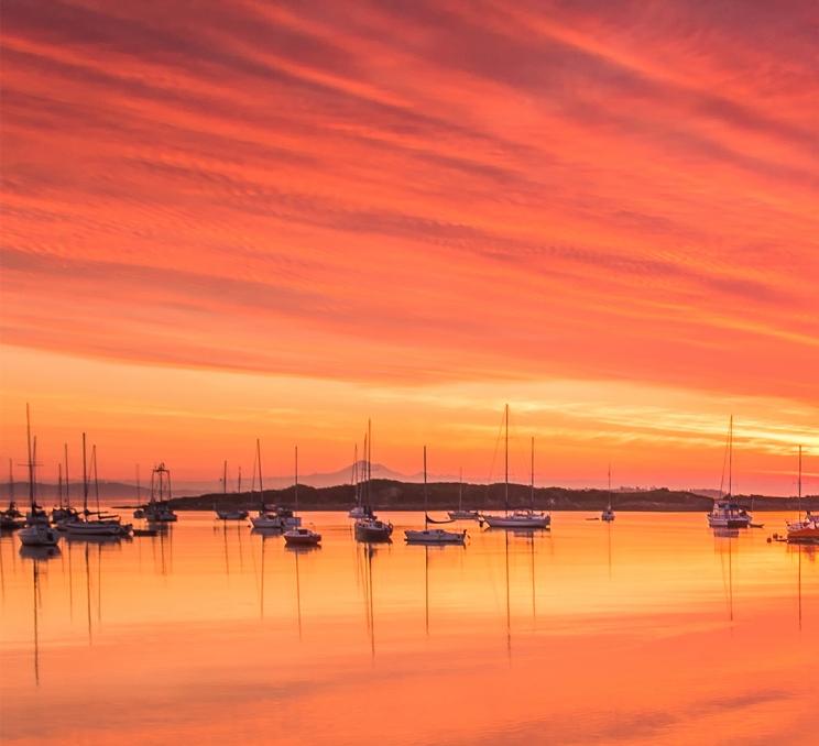 A sunrise over the Haro Strait above Sail Boats in Oak Bay in Greater Victoria, BC