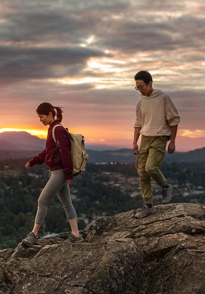 A young couple hikes across the summit of PKOLS (formerly Mount Douglas) Regional Park in Greater Victoria, BC