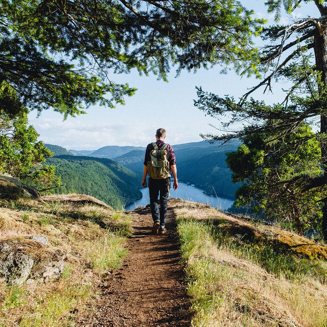 A lone hiker walks along a forested path in Gowlland Tod Provincial Park in Victoria, BC