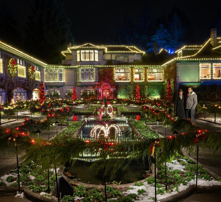 A couple watches a fountain in a garden during The Butchart Gardens Magic of Christmas Holiday Light display.