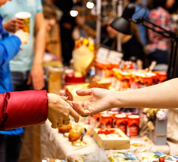 A person hands over a holiday ornament at a Christmas Market