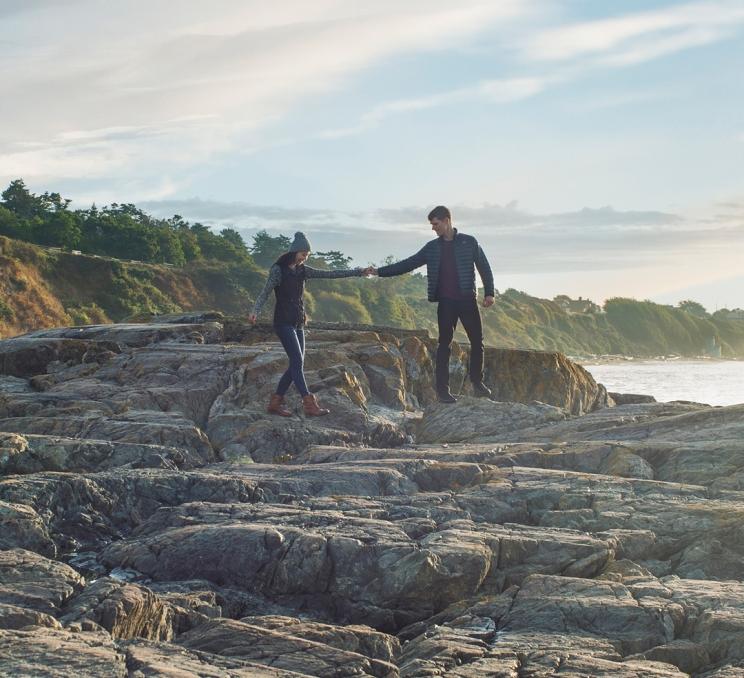 A couple walks hand-in-hand along Dallas Road Beach in Victoria, BC
