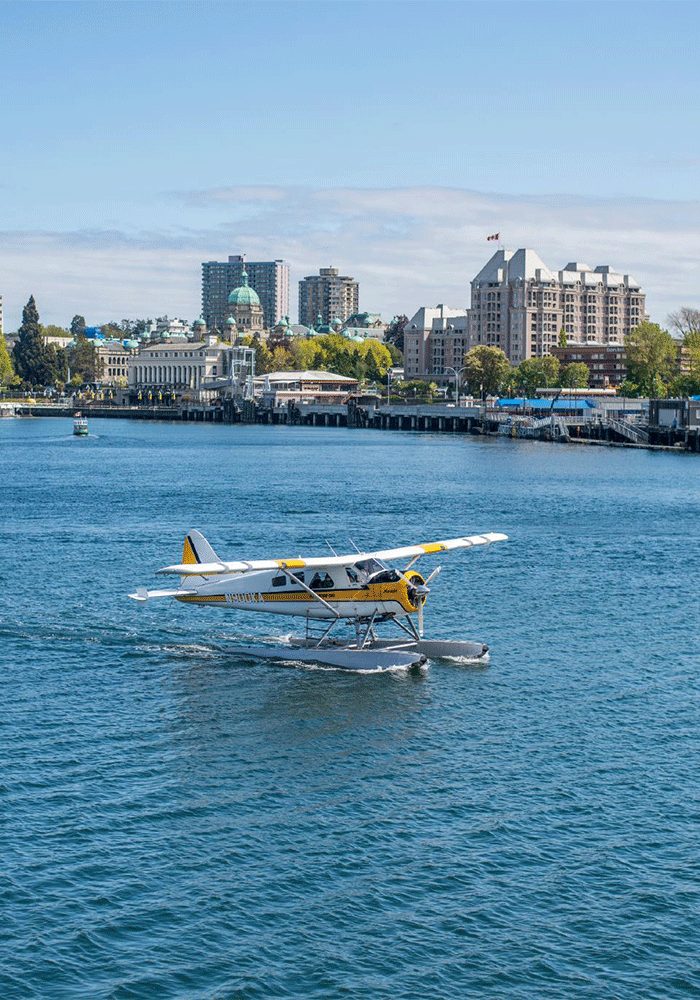 A Kenmore Air seaplane moving across Victoria, BC's Inner Harbour