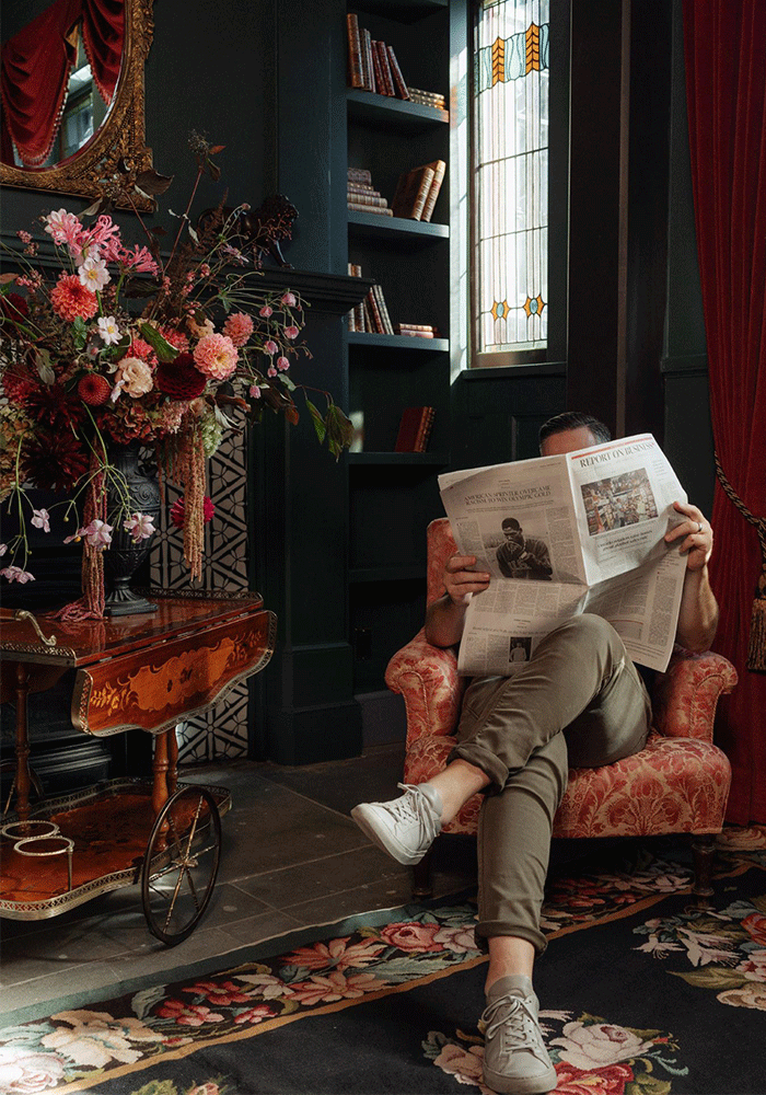A person reading a newspaper while sitting in a reading room at Rosemead House in Victoria, BC