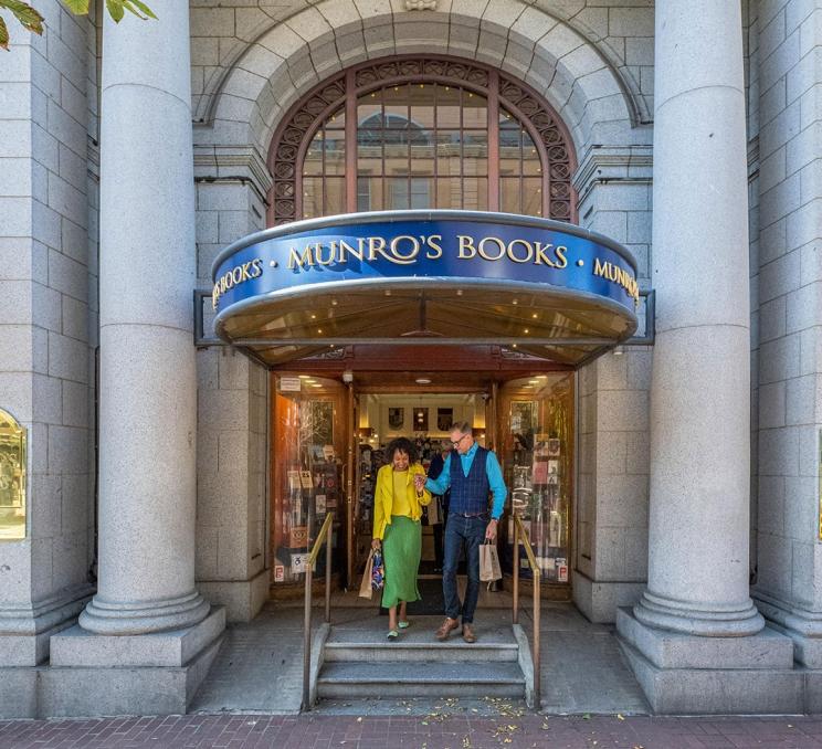 A couple walking out of Munro's Books on Government Street in Victoria, BC after shopping