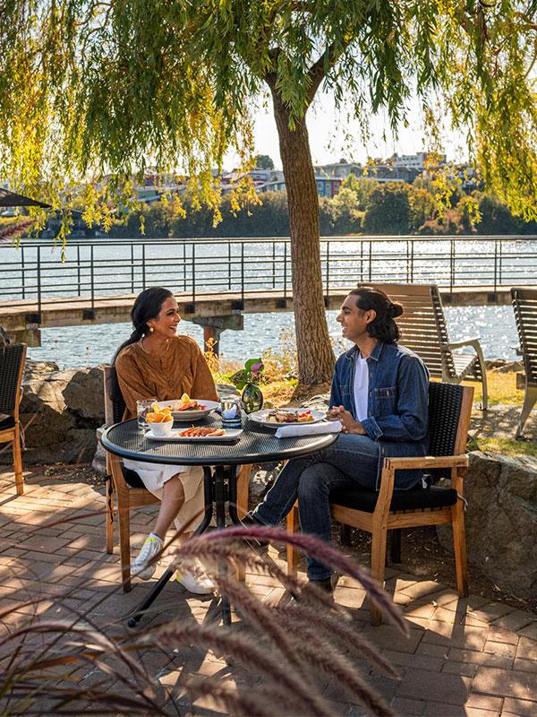A young couple dines on the patio at Glo Restaurant + Patio situated along Victoria, BC's Upper Harbour