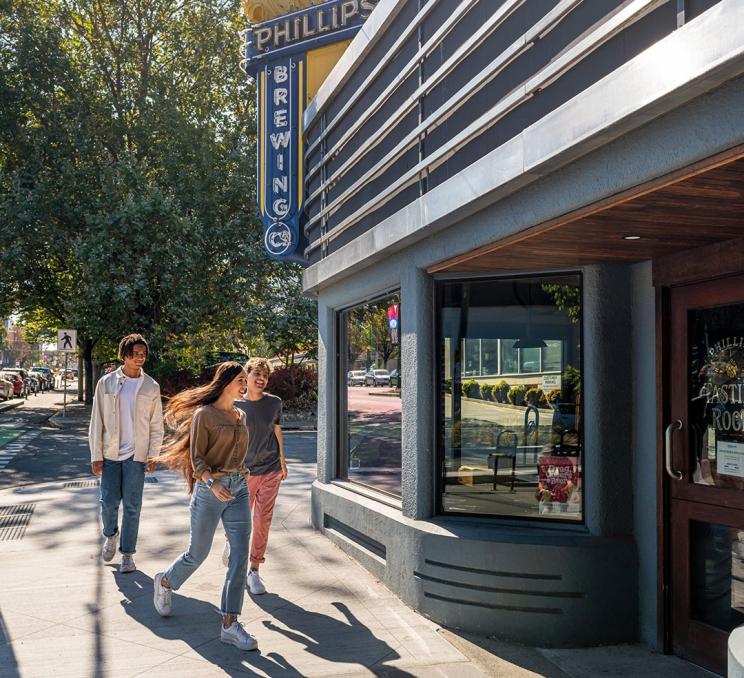 Three friends walking along Government Street turn to go into Phillips Brewing & Malting Co's tasting room in Victoria, BC