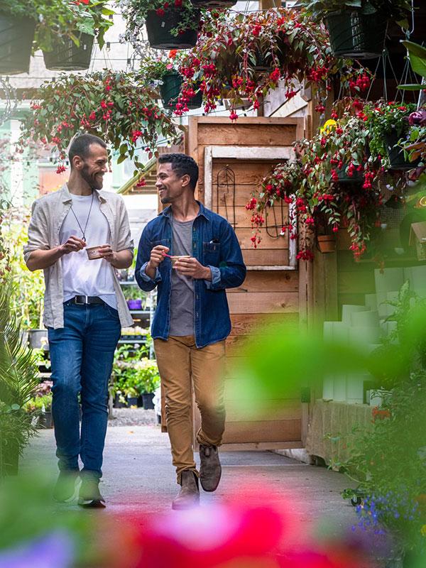 A male couple eating ice cream walks through a flower shop on Cook Street in Victoria, BC