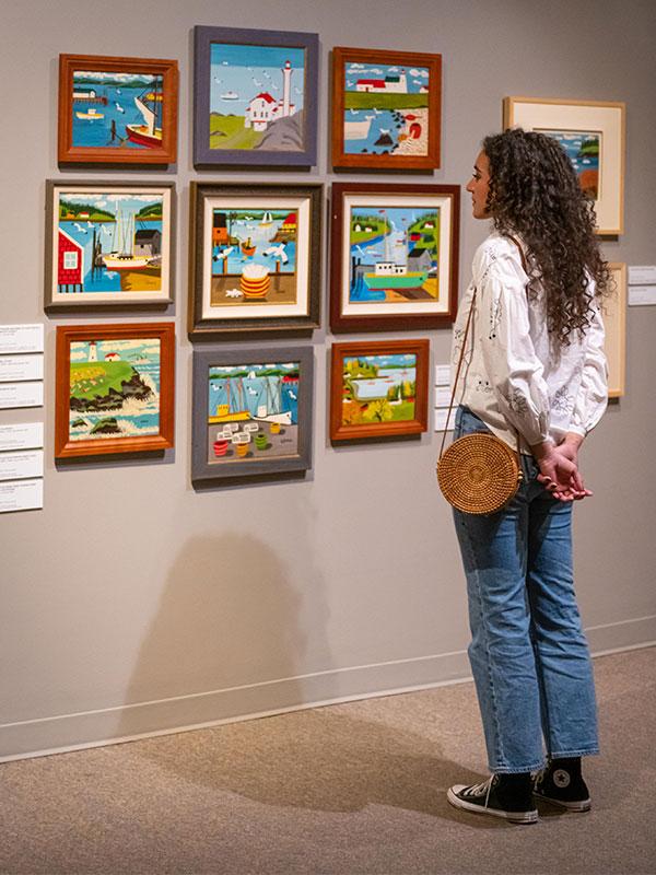 A woman dressed in a white shirt and jeans examines artwork on the wall at the Art Gallery of Greater Victoria in Victoria, BC's Rockland neighbourhood