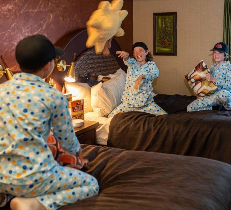 Three boys having a pillow fight on the beds at Hotel Zed in Victoria, BC