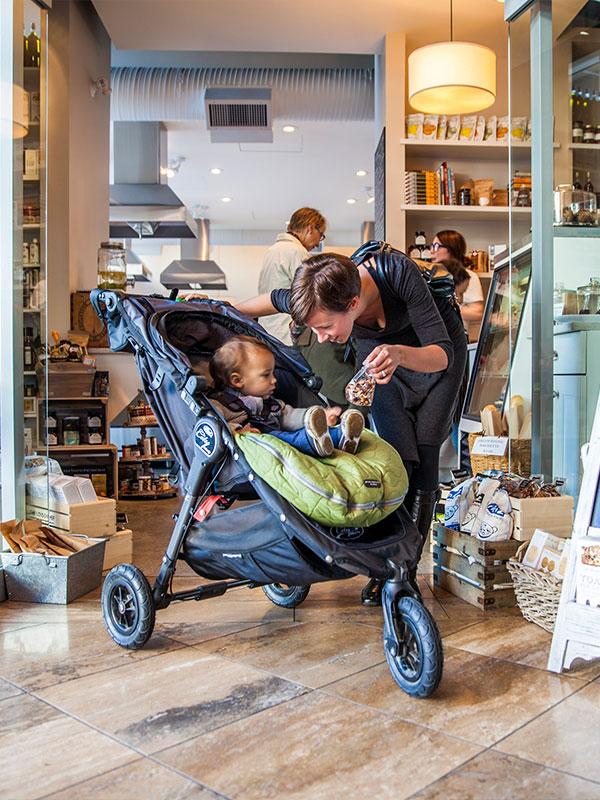 Adult with a child in a stroller inside a local shop in Victoria BC, browsing snacks and specialty foods