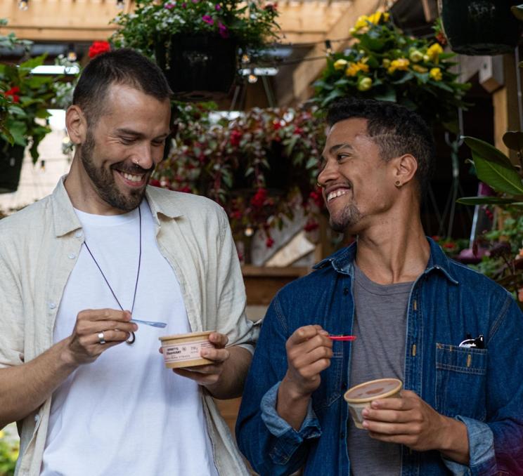 A male couple enjoys ice cream while walking through a garden shop in Cook Street Village in Victoria, BC's Fairfield neighbourhood