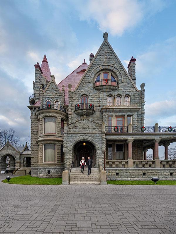 A couple walks hand-in-hand down the steps of Craigdarroch Castle in Victoria, BC