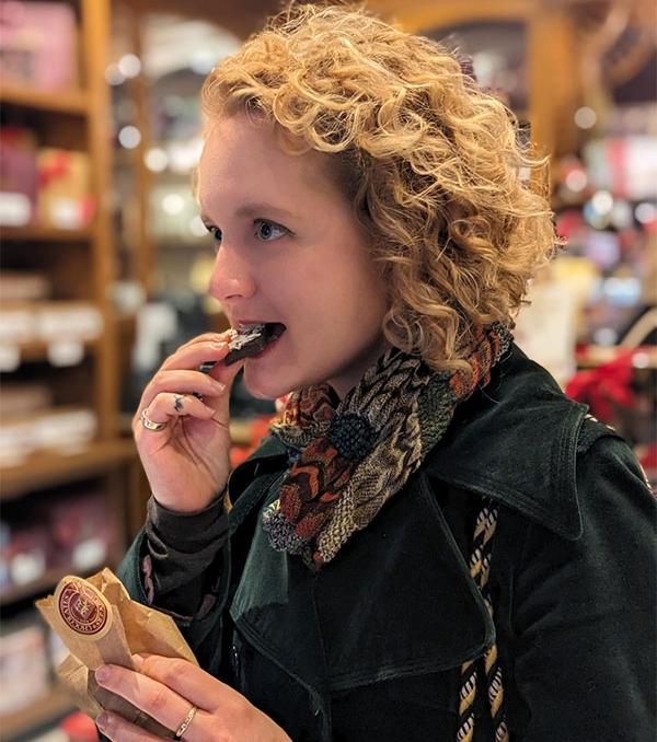 A woman bites into a sweet during an Off the Eaten Track food tour in Victoria, BC
