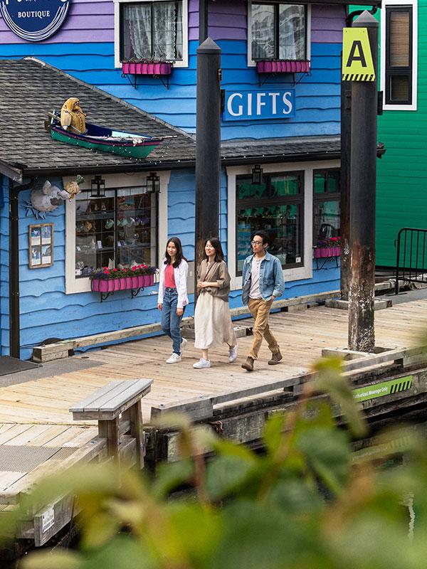 A family walks along the docks at Fisherman's Wharf past a brightly coloured gift shop