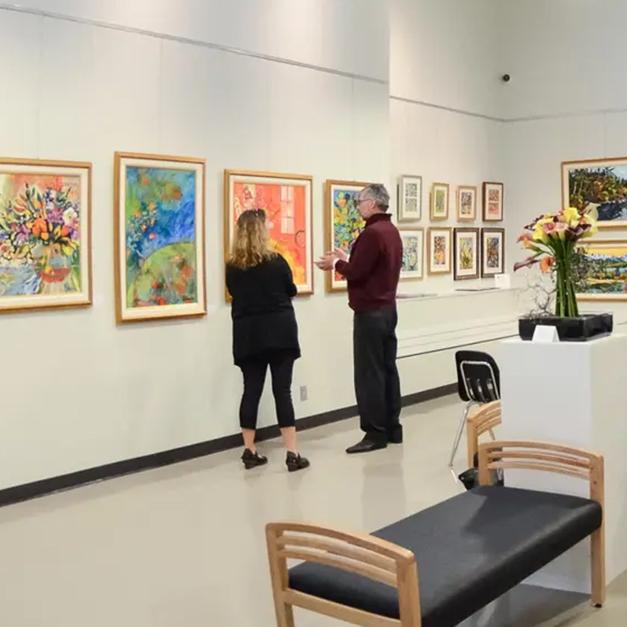 Two people examine the artwork at the Arts Centre @ Cedar Hill Recreation Centre in Saanich, BC