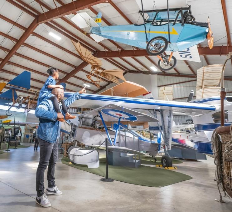 A father gives his daughter a piggyback ride through the BC Aviation Museum in Victoria, BC