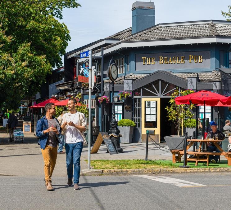 A couple eats ice cream as they walk down Cook Street past the Beagle Pub in Victoria, BC