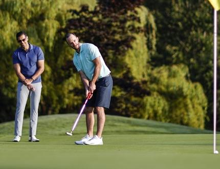 A golfer wearing blue putts while on a green at a Victoria, BC golf course