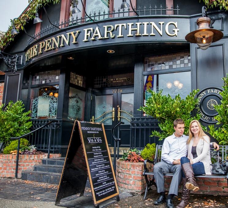 A couple sits on a bench outside the Penny Farthing Pub in the Oak Bay neighbourhood of Victoria, BC