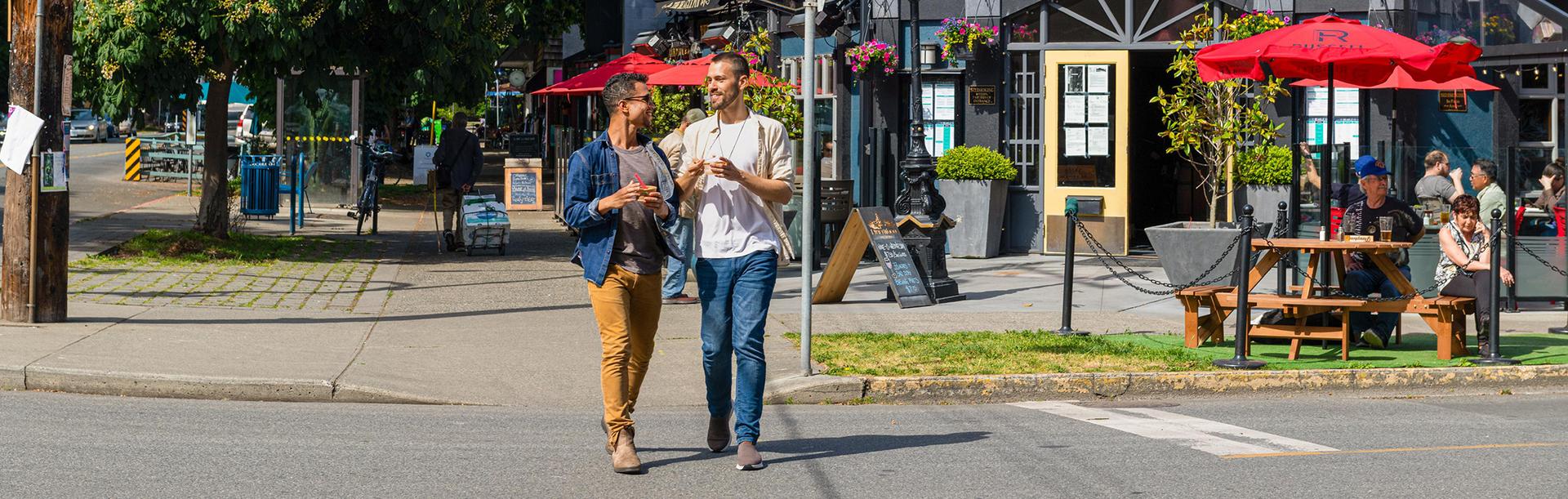 A couple walks down Cook Street Village while enjoying ice cream in Victoria, BC