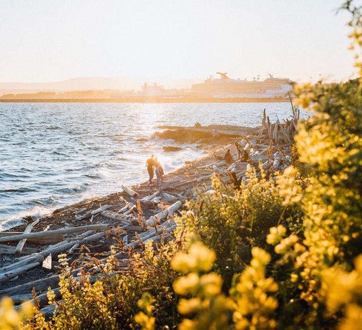 A couple takes a sunset walk along Dallas Road Beach in Victoria, BC