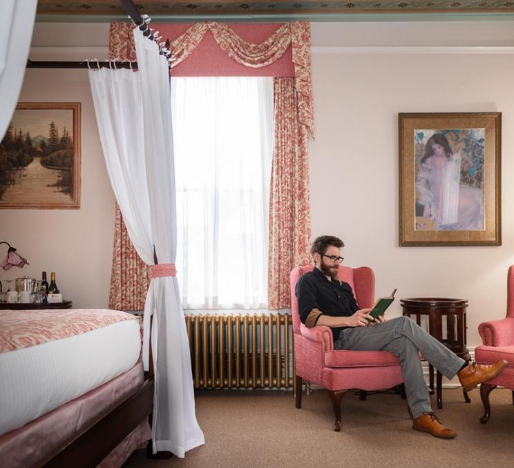 A man reads a book in a room at the Pendray Inn and Teahouse in Victoria, BC
