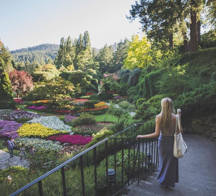 A woman walks down the staircase into the Sunken Garden while holding an ice cream cone at The Butchart Gardens in Victoria, BC