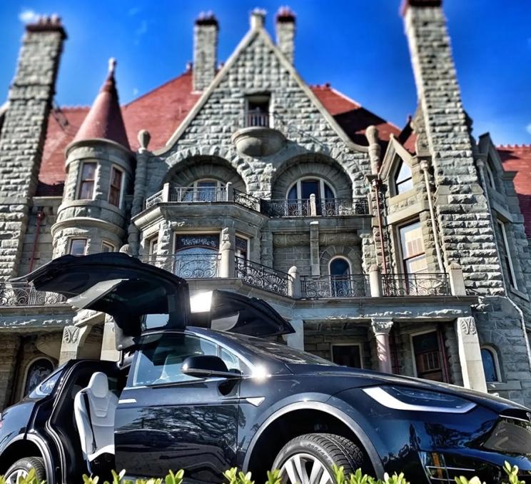 A black Tesla sits out front of Craigdarroch Castle in Victoria, BC
