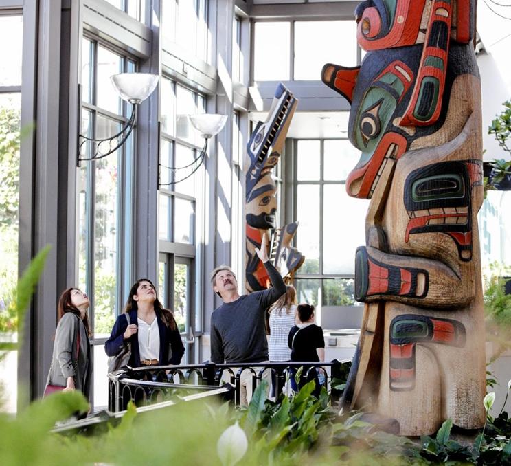 A group of delegates admire the Indigenous artwork in the Totem Atrium of the Victoria Conference Centre in Victoria, BC
