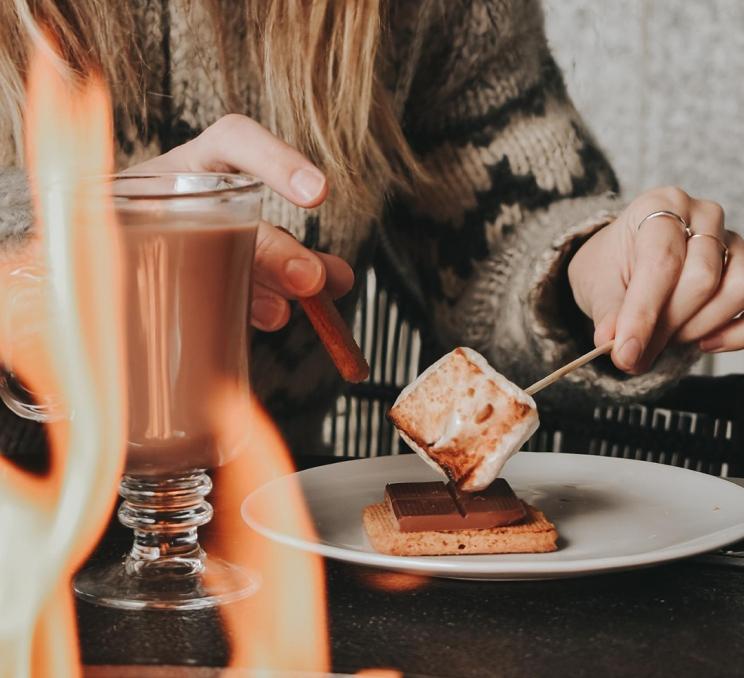 A woman prepares a s'more to enjoy with her hot chocolate, fireside, on the Veranda at the Fairmont Empress in Victoria, BC