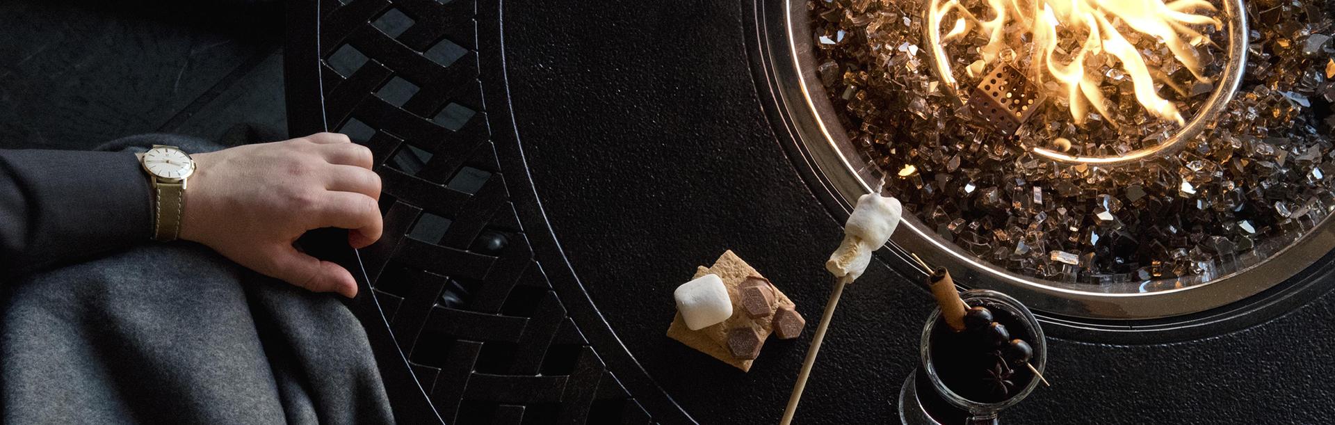A person roasting s'mores over a fire during Winter on the Veranda at the Fairmont Empress in Victoria, BC