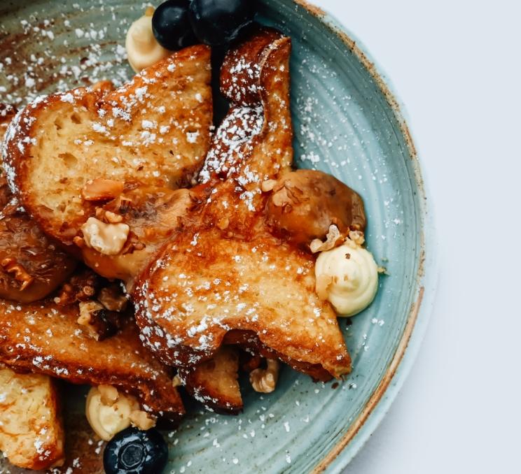French toast topped with caramelized fruit, blueberries, and powdered sugar at Callisto in Victoria, BC
