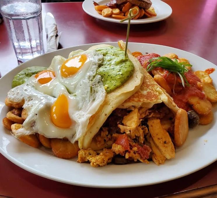 Hearty brunch platter at Floyd's Diner featuring sunny-side eggs, pancakes, breakfast potatoes, and savoury hash