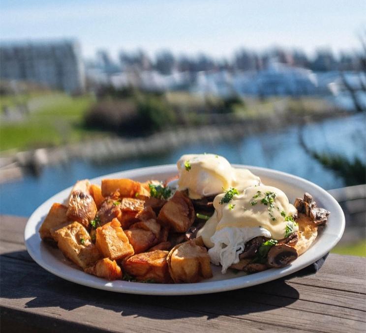 Eggs Benedict with roasted breakfast potatoes overlooking Victoria's Inner Harbour at Spinnakers Gastro Brewpub