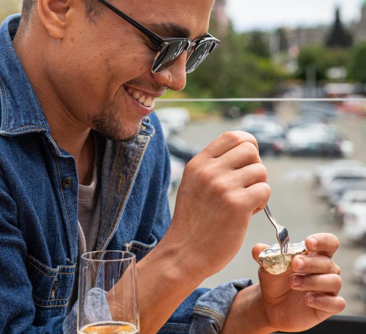 A man eats an oyster on the patio at Finn's Seafood, Chops & Cocktails in Victoria, BC