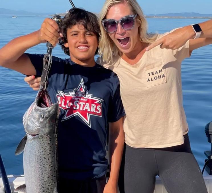 A mom and son show off a salmon they caught during a fishing charter in Victoria, BC
