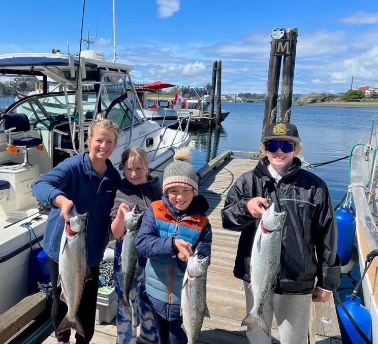 A family celebrates their catch with No Limit Fishing Charters in Victoria, BC