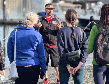 An Indigenous Guide from Songhees Tours leads a walking tour of the Inner Harbour in Victoria, BC
