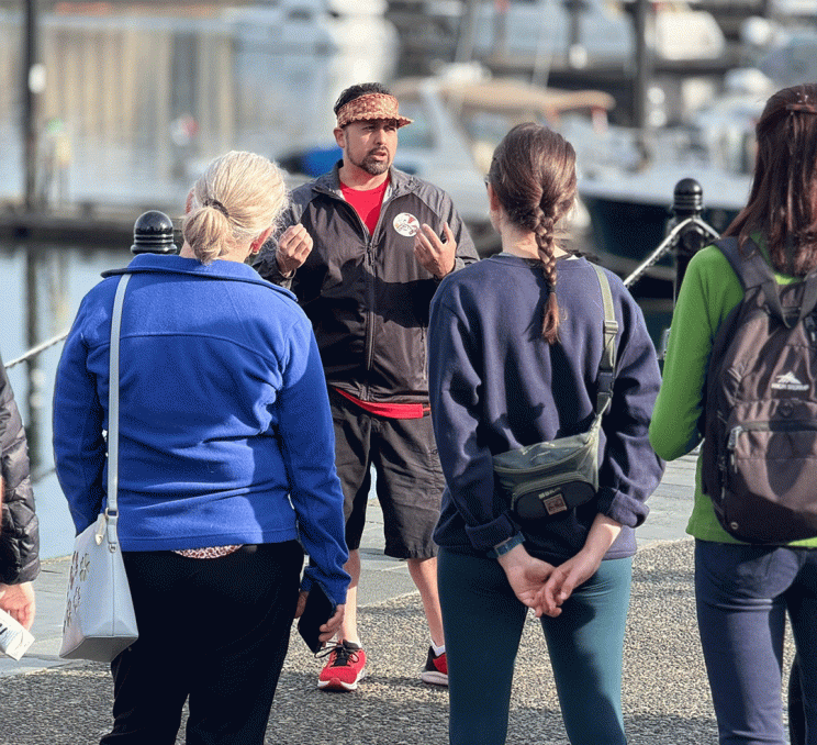 An Indigenous Guide from Songhees Tours leads a walking tour of the Inner Harbour in Victoria, BC