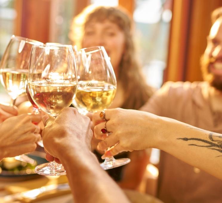 A group of friends cheers wine glasses in the Arbutus Room in Victoria, BC