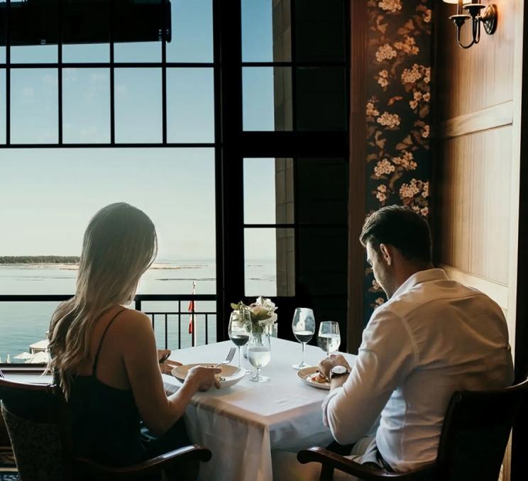 A couple dines with a romantic view at The Dining Room at the Oak Bay Beach Hotel in Victoria, BC