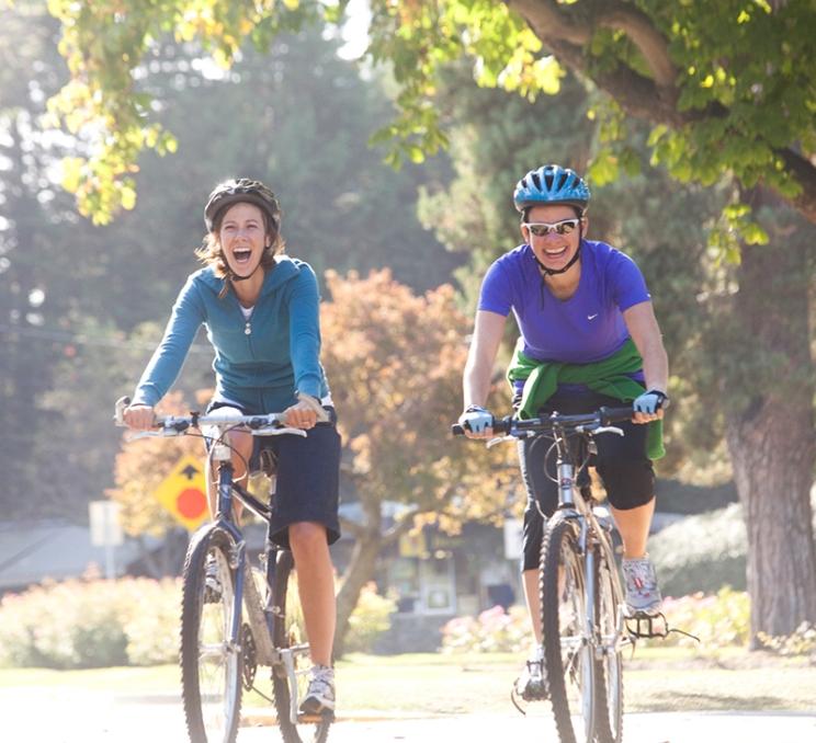 Two people ride bikes down a street in Victoria, BC